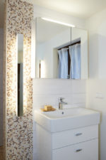 Mosaikfliesen und ein Spiegelschrank machen den Waschplatz zu einem optischen Hingucker im Bad